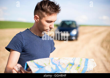 Photo d'un voyageur stationné sa voiture par le côté d'une route, perdu et la lecture de la carte. Se concentrer sur la carte et de sexe masculin. Banque D'Images