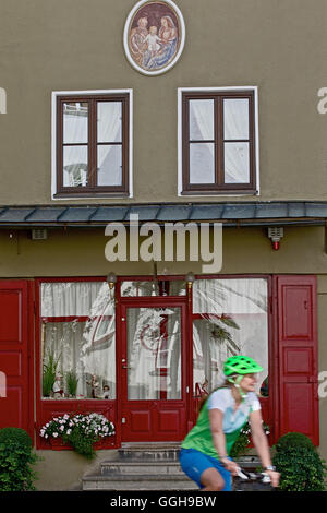 Cycliste femme passant d'une chambre avec une porte rouge, Burghausen, Bade-Wurtemberg, Bavière, Allemagne Banque D'Images