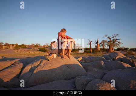 Mère et fils assis sur un rocher, Kubu Island, Makgadikgadi Pans National Park, Botswana Banque D'Images