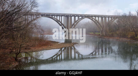 Une réflexion symétrique, une route sur un pont à la fin de l'automne brumeux matin sur la Petite rivière Miami dans le sud-ouest de l'Ohio, USA Banque D'Images