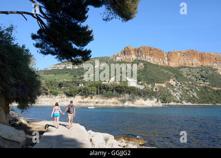 Jeune couple de touristes marcher de pair le long d'une côte avec Cap Canaille et les falaises en arrière-plan Cassis Provence Banque D'Images