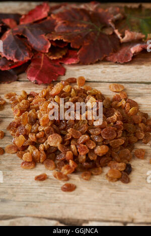 Raisins dorés sur table en bois avec feuilles de vigne d'automne Banque D'Images