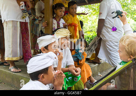 Les enfants balinais jouant avec l'Allemand jeune garçon, 3 ans, vêtements traditionnels à la cérémonie du temple, la religion balinaise, poussette, je Banque D'Images