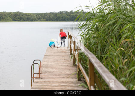 Deux garçons avec l'épuisette sur une jetée dans un lac, la Réserve de biosphère de Schorfheide-Chorin, Neudorf, Friedenfelde, Uckermark, Brandebourg Banque D'Images