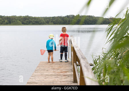 Deux garçons avec l'épuisette sur une jetée dans un lac, la Réserve de biosphère de Schorfheide-Chorin, Neudorf, Friedenfelde, Uckermark, Brandebourg Banque D'Images