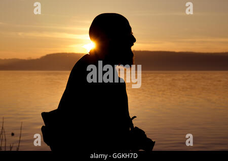 Vieil homme comme touriste avec appareil photo sur le lac de Constance au coucher du soleil qui se profile Banque D'Images