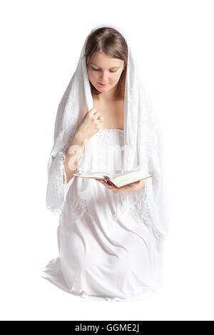 Jeune femme avec un voile, à genoux et la lecture de la Bible. Isolé sur fond blanc Banque D'Images
