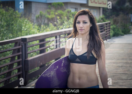 Portrait femme transportant skimboard sur boardwalk Banque D'Images