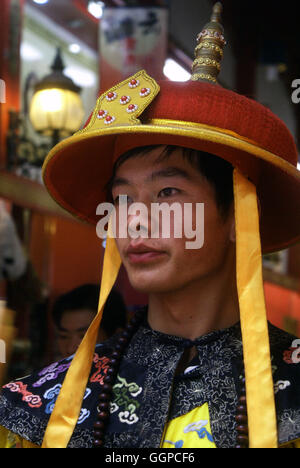 Un jeune homme habillé en costume d'affaires à une batterie boutique de souvenirs. La rue Qianmen, Beijing - Chine. Banque D'Images