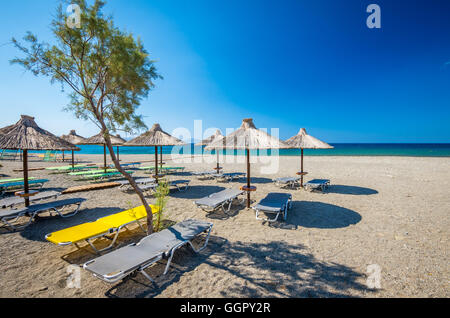 Parapluie de paille sur une plage de sable à la Grèce. Chaises de plage avec parasols sur une magnifique plage à l'île de Crète. Banque D'Images