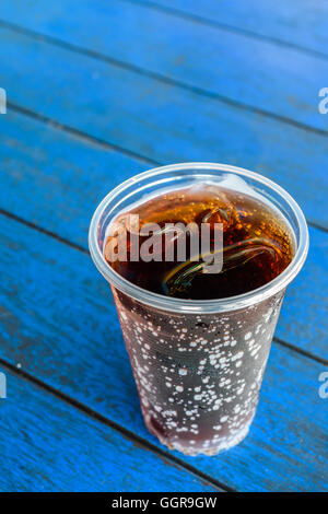 Cola boissons avec des glaçons sur bleu en bois planche Banque D'Images