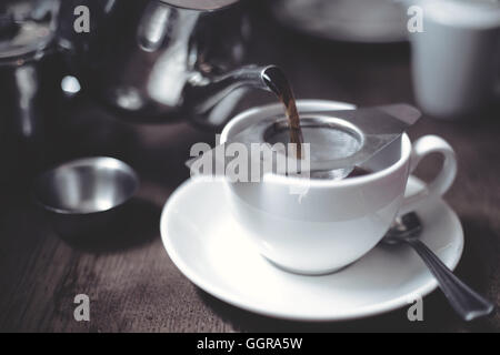 Close up de verser le thé dans la théière tasse sur la table en bois Banque D'Images