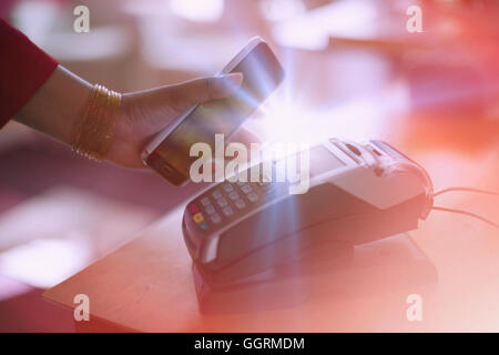 Indian woman paying with cell phone la technologie NFC Banque D'Images