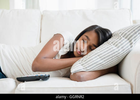 Mixed Race girl sleeping on sofa avec oreiller Banque D'Images