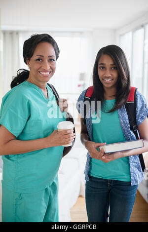 Smiling nurse et sa fille laissant house en matinée Banque D'Images