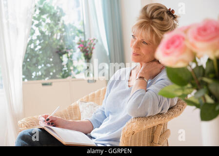 Older Caucasian woman writing in journal Banque D'Images