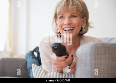 Older Caucasian woman laying on sofa watching television Banque D'Images