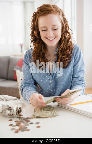 Caucasian woman counting money de savings jar Banque D'Images