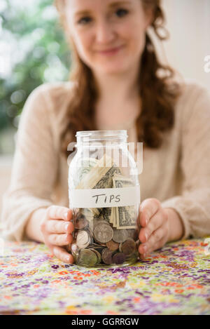 Caucasian woman montrant l'argent in tip jar Banque D'Images