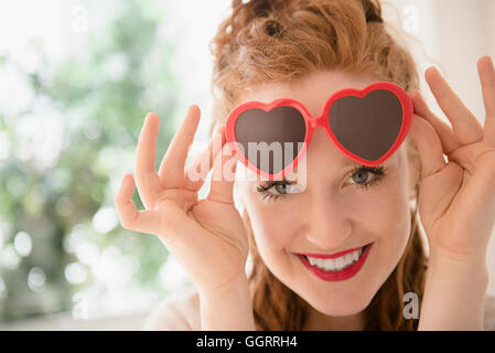 Businessman peeking de lunettes en forme de coeur Banque D'Images