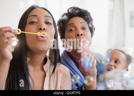 Black multi-generation family blowing bubbles avec bubble wand Banque D'Images