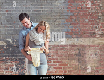 Smiling Caucasian man et future mère holding onesie Banque D'Images