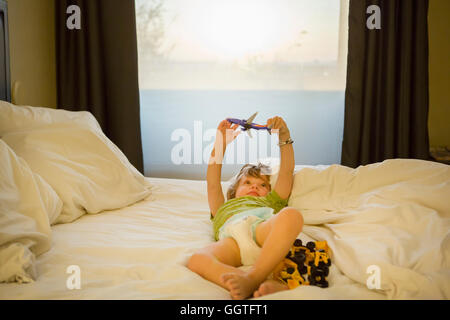 Boy with airplane on bed Banque D'Images