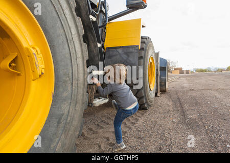 Young boy climbing ladder sur le tracteur Banque D'Images