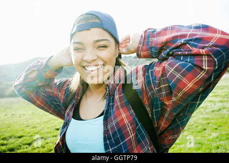 Smiling Mixed Race woman backpacking in field Banque D'Images