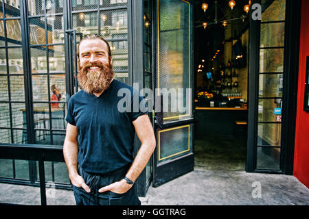 Caucasian man with beard smiling on sidewalk Banque D'Images