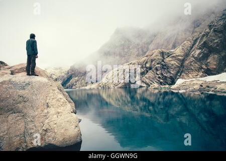 Man Traveler Standing alone on stone cliff lac et montagnes brumeuses sur le contexte de vie de plein air concept Voyage Banque D'Images
