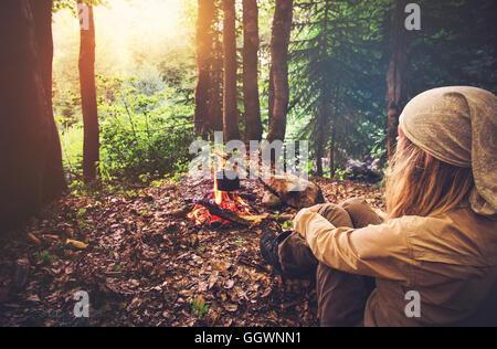 Woman traveler relaxing in forest et la cuisson des aliments dans la bouilloire sur le feu de vie voyage vacances concept bivouac pique-nique en plein air je Banque D'Images