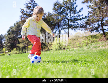 Happy Young boy playing football outdoors Banque D'Images