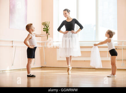 En danse classique Catégorie : jeune garçon et fille donnant des fleurs et voile à étudiant plus âgé alors qu'elle danse en pointe Banque D'Images