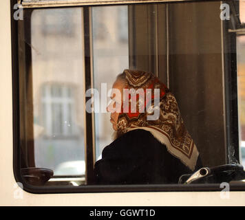 Femme au foulard à motifs et manteau noir assis par fenêtre sur le bus à Sarajevo en Bosnie Herzégovine Banque D'Images