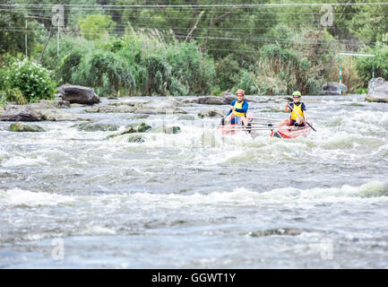 Jeune couple sur un catamaran gonflable jusqu'aviron le flux Banque D'Images