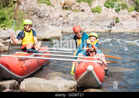 Famille de trois personnes jouant avec les pistolets à eau près de l'aviron, catamaran gonflable active summer concept loisirs Banque D'Images