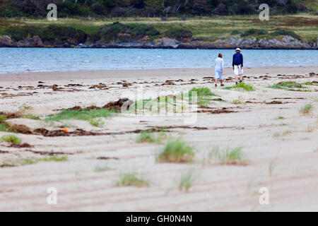 Un couple bénéficiant d'une promenade le long du rivage de la plage Newborough, Anglesey, Pays de Galles, Royaume-Uni Banque D'Images
