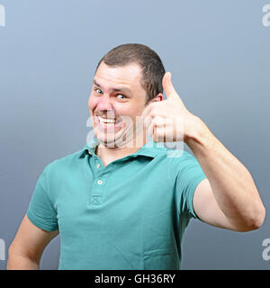 Portrait of a man showing thumb up ou ok signer contre l'arrière-plan gris Banque D'Images