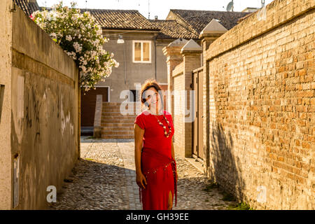 Mais le véritable élégant femme âgée avec yeux fille smiling marcher dans les ruelles étroites entre les murs de briques d'un ancien village médiéval en Italie Banque D'Images