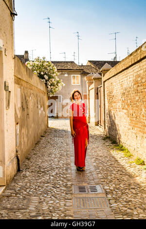 Mais le véritable élégant femme âgée avec yeux fille smiling marcher dans les ruelles étroites entre les murs de briques d'un ancien village médiéval en Italie Banque D'Images
