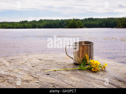 Mug en acier inoxydable sur la pierre près de l'eau sur fond nature Banque D'Images