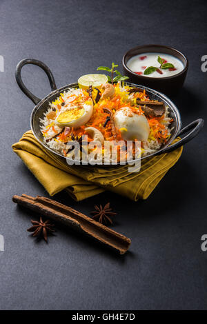 Riz Basmati cuit lentement avec Masala oeuf et épices servi dans kadhai ou kadai avec une trempette au yogourt, selective focus Banque D'Images