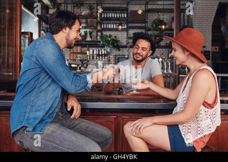 Portrait de jeunes gens modernes assis dans le café et d'avoir leur boisson. Groupe d'amis au café un toasting drinks. Banque D'Images