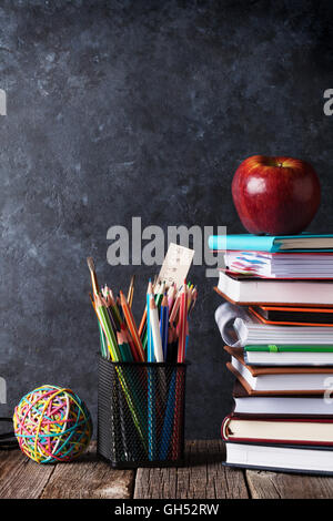 Des blocs-notes, des fournitures et de l'apple en avant du tableau. Retour à l'école avec copie espace concept Banque D'Images