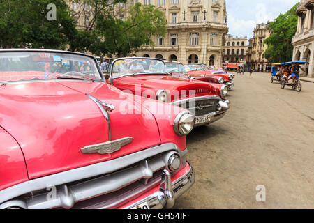 American Pontiac et Chevrolet Classic cars roses et rouges alignés dans le Parque Central, La Vieille Havane, Cuba Banque D'Images