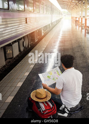 Voyageur asiatique homme avec effets personnels en attente de voyager par train à la gare de Chiang Mai, Thaïlande. Banque D'Images