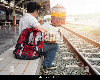 Voyageur asiatique homme avec effets personnels en attente de voyager par train à la gare de Chiang Mai, Thaïlande. Banque D'Images