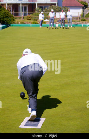 Les personnes âgées à jouer un match de la concurrence parfaite sur un bowling green en plein soleil. Banque D'Images