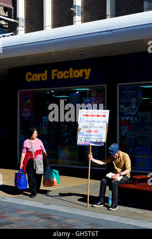 Young man holding up sign advertising les petits déjeuners et un café local, Darlington, County Durham, England UK Banque D'Images